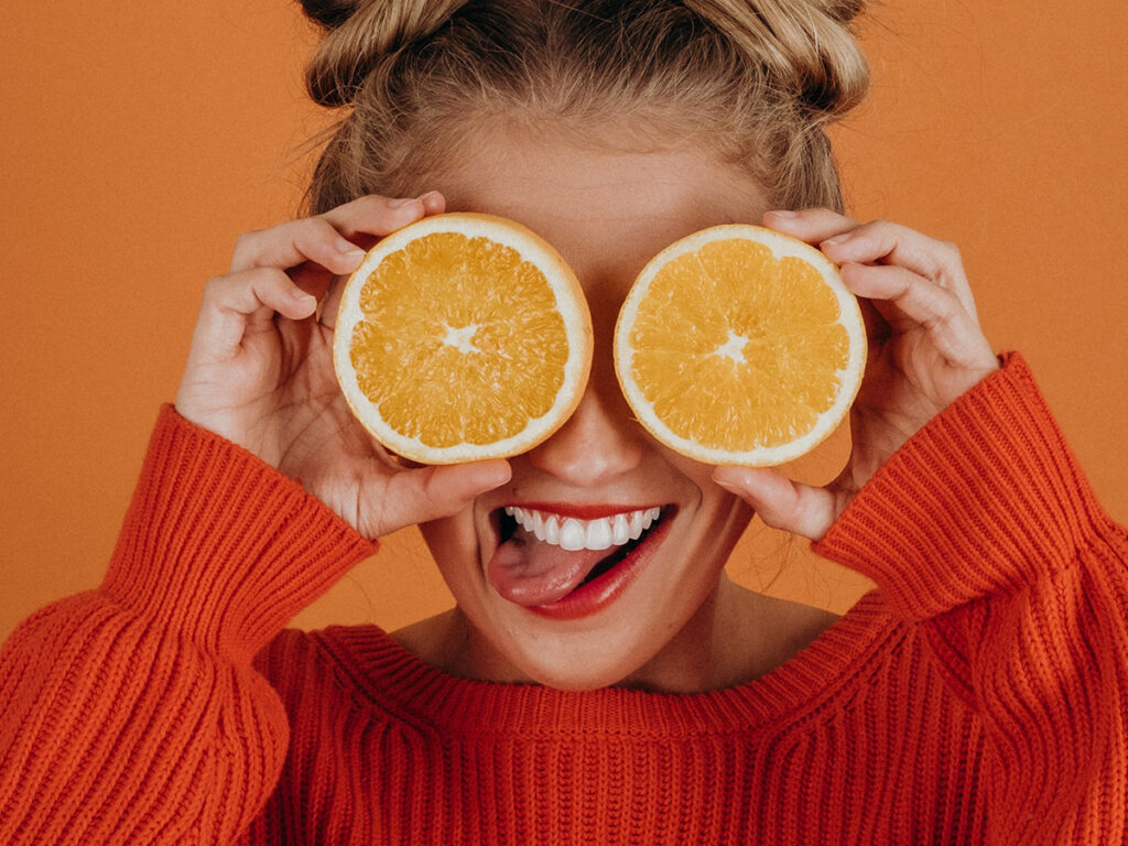 Woman holding orange slices to her eyes
