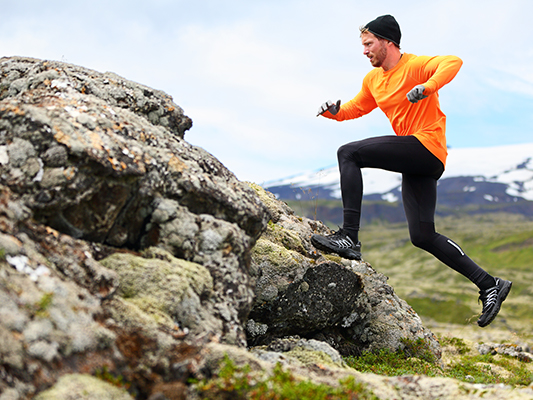 Man trail running and running up rocks.